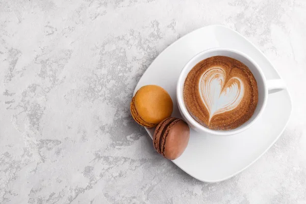 Cup of coffee and two macarons on the grey stone background  with copy space, flatlay top view