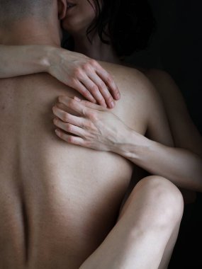 Bir erkek ve bir kadın birbirlerinin kollarında. Kadın bacakları ve kolları güçlü kaslı bir erkeği kucaklıyor. Çıplak bedenler..