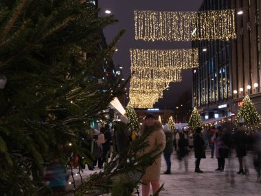 Helsinki, Finlandiya - 11 / 19 / 2022: Helsinki 'nin merkez caddelerinde Noel süslemeleri ve aydınlatma. Ön planda bir Noel ağacının dalları.