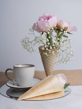 Bir buket pembe şakayık ve bir fincan çayla sanatsal bir hayat. Boynuzlu pembe şakayık çiçeği. Tasarım için çiçekler. Dikey fotoğraf.