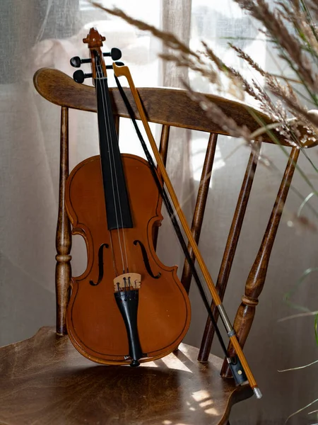 Vintage Βιολί Ένα Τόξο Μια Ξύλινη Καρέκλα Από Παράθυρο Φωτίζεται — Φωτογραφία Αρχείου