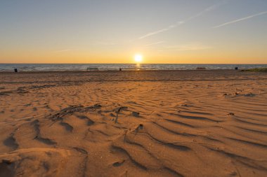 Close-up of the sea sandy beach. Panoramic beach landscape. Orange and golden sunset sky. Calm relaxing sunny summer mood. Holiday banner for recreation. Estonia, Narva-Jyesuu.