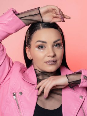 Pembe arka planda deri ceketli güzel bir esmerin portresi. Yakın plan. Yüzünde parlak bir parıltı var.