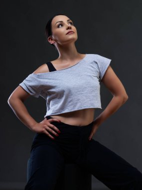 Gri bir arka planda siyah elbiseli bir kadın dansçı.