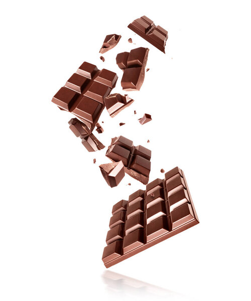 Целые и разбитые плитки темного шоколада в воздухе на белом фоне