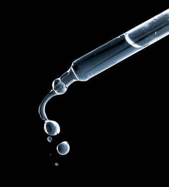 Siyah arka planda damlayan damlalarla kozmetik pipeti