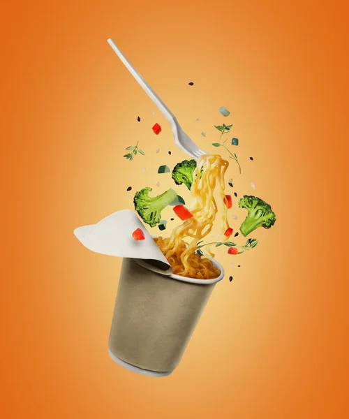 Instant noodles with food ingredients fly out from a cardboard cup