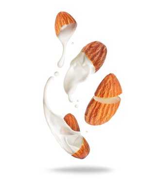 Beyaz arka planda izole edilmiş havadaki kırık bademlerden süt dökülüyor