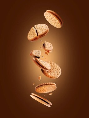 Kahverengi arka planda çikolatalı çıtır kurabiyeler uçuşuyor.