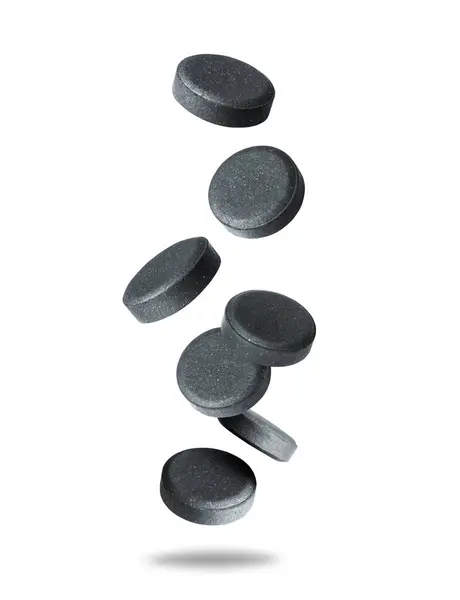 stock image Levitation of activated charcoal pills in the air isolated on a white background