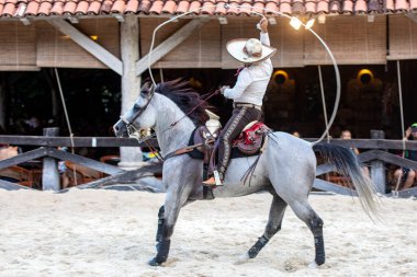 Mexican equestrians with a magnificent exhibition of running lasso movements on Aztec horses of great lineage, this is a unique show at Xcaret Park in Mexico. clipart