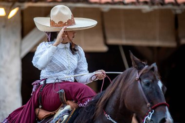 Güzel bir Meksikalı kadın binicilik gösterisi. Geleneksel bir şapkası olan Aztek atı dörtnala giderken Meksika 'daki Xcaret Park' ta benzersiz ve inanılmaz bir gösteri..