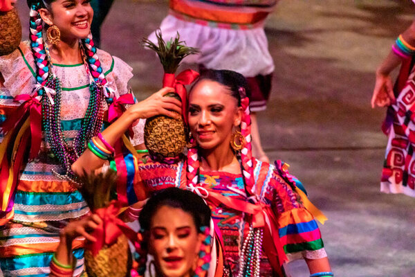 Xcaret, Mexico - January 27, 2023: Beautiful Mexican women performing the folkloric dance of the pineapple flower at Xcaret park in the middle of the tropical jungle of the Mayan Riviera in Mexico.