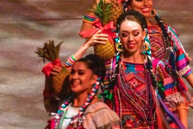 Xcaret, Mexico - January 29, 2023: Women dancing and enjoying the folkloric dance of the Oaxaca pineapple flower at Xcaret Park, in the middle of the tropical jungle of Mexico's Mayan Riviera.