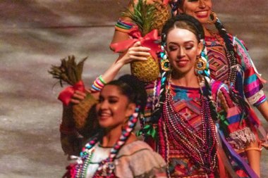 Xcaret, Mexico - January 29, 2023: Women dancing and enjoying the folkloric dance of the Oaxaca pineapple flower at Xcaret Park, in the middle of the tropical jungle of Mexico's Mayan Riviera. clipart