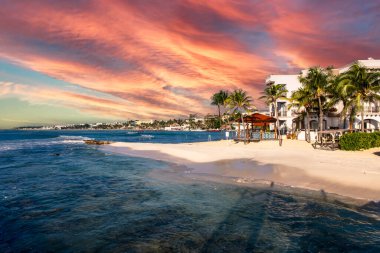 Panoramic view of the city of Playa del Carmen in the famous Mayan Riviera bathed by the Caribbean Sea with an orange sunset, in the middle of the tropical jungle of Mexico.