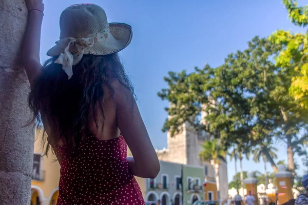 Woman with hat enjoying the Mexican city of Valladolid, looking at the cathedral of San Servacio in the center of the city. Travel concept.