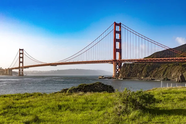 stock image The Golden Gate Bridge over San Francisco Bay as seen from a green meadow overlook. The most famous bridge in the state of California in the USA. Bridge concept of America.