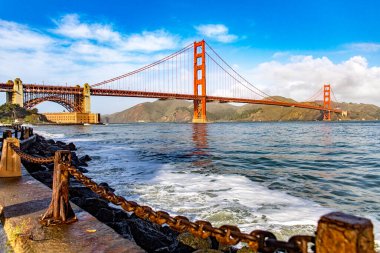 Kaliforniya eyaletindeki Golden Gate Köprüsü mavi gökyüzü ve okyanusun altında. California şehrinin rıhtımına bakış açısından görüldü. Amerikan köprü kavramı.