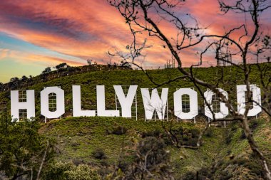 Amerika Birleşik Devletleri 'nin Kaliforniya eyaletinde gün doğumunda ve batımında güzel bir turuncu ve kırmızımsı gökyüzünün altında, Amerikan şehri Los Angeles' taki ünlü Hollywood tabelası..