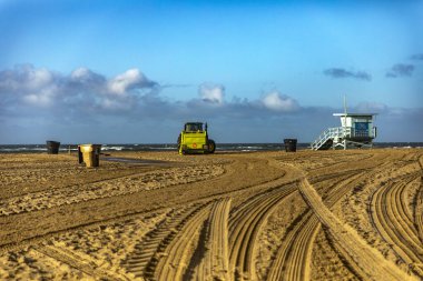 Traktör, Amerika Birleşik Devletleri 'nin Kaliforniya eyaletindeki Santa Monica şehrinde güzel bir Kuzey Amerika gökyüzünün altında kumları düzenliyor ve sürüyordu..