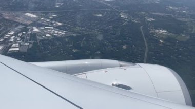 New York 'un (ABD) son teknoloji ürünü geniş gövdeli ticari bir uçağın penceresinden şehri ve havaalanına yaklaşan uçağın motorunu gösteren hava görüntüsü.