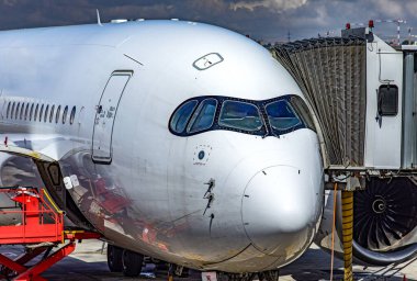 Airbus A350-900, bu yeni nesil geniş gövdeli bir uçak. Uzun menzilli seyahat için ideal, park edilmiş ve bir havaalanından havalanmak üzere yolcular tarafından bindiriliyor..