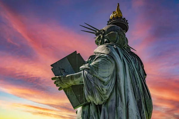 The lady of the Big Apple, better known as the Statue of Liberty of New York in the middle of Manhattan under a red sky at dawn.