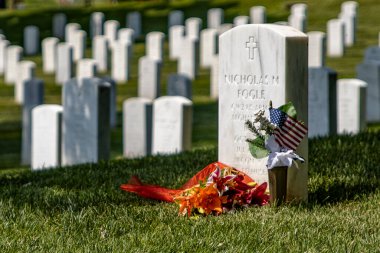 Washington DC, ABD; 2 Haziran 2023: Askeri dünyadaki en ünlü mezarlık olan Arlington Ulusal Mezarlığı 'nda çiçek ve bayrak taşıyan beyaz mermer taş.