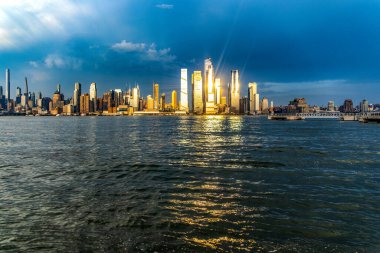 New York 'un ufuk çizgisi ve New York' un büyük elması Hudson Nehri 'nin üzerinde gün batımının altında ve güneş ışınları binalara yansıyor..