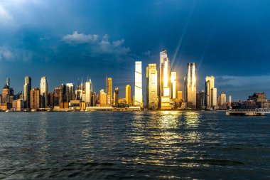 New York ve Büyük Elma 'nın muhteşem ufuk çizgisi Hudson Nehri' nde gün batımının altında ve güneş ışınları binalara yansıyor..