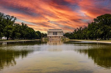 Abraham Lincoln Anıt Tapınağı, Washington DC 'deki National Mall' da gün batımında turuncu bir gökyüzünün altındaki yansıma havuzuna yansıdı..