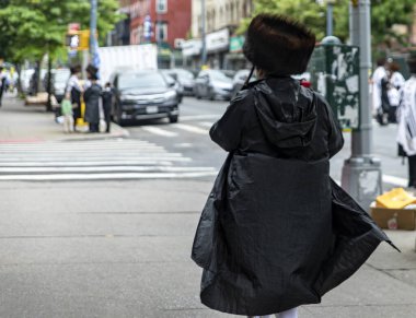 Brooklyn 'deki Williamsburg Yahudi mahallesinde Şabat' ın keyfini çıkaran bir ortodoks Yahudi, New York 'ta büyük bir topluluğun bulunduğu tipik elbisesiyle (ABD)).