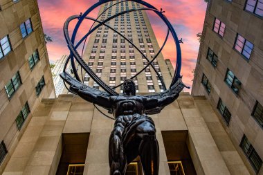 New York, ABD; 4 Haziran 2023: Atlas, Manhattan 'ın merkezindeki Uluslararası Bina' nın avlusunda, günbatımında veya gündoğumunda Rockefeller Center 'ın arka planında bulunan bronz bir heykel..
