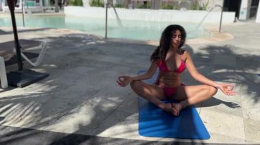 Çekici bir bikini mayosuyla yoga yaparken Karayipler 'deki büyük lüks bir otelde yaz tatilinin tadını çıkaran genç ve sportif bir kadın dinleniyor..