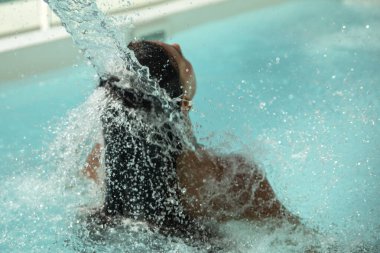 Sıcak tropikal ışınlar altında ve tropikal ve paradisikal bir çevre ve manzara altında, Karayipler 'de berrak bir havuzda serinleyen seksi bikinili bir turist..