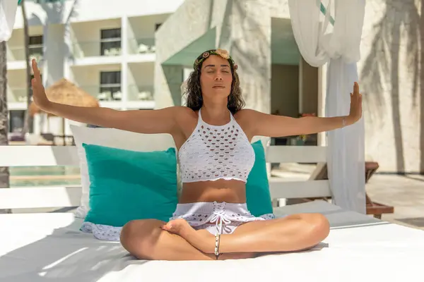 stock image Experience the essence of serenity as a woman in white effortlessly flows through yoga poses on a balinese bed, embodying a path towards relaxation and well-being