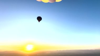 Luxor 'un sihri sıcak hava balonuyla gökyüzünde süzülürken ve güneşin ufku canlı sıcak renklerle boyadığını izlerken. Mısır 'ın kadim güzelliklerinin kuşbakışı güzelliği.
