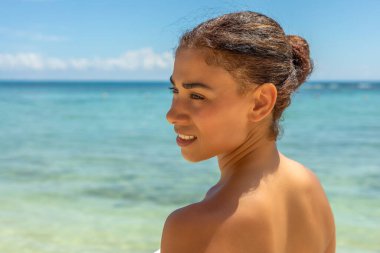 Beyaz bikinili çarpıcı bir kadın, kristal berrak sularla çevrili el değmemiş bir sahilde poz veriyor. Güzelliği ve tropikal manzarası mükemmel bir an yaratıyor..