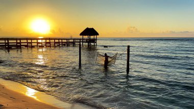 Karayipler 'de hamakta sallanan seksi bir kadın güzel bir turuncu güneşin altında bu rahatlatıcı bir deneyim ve harika ve sağlıklı bir yaşam tarzı..