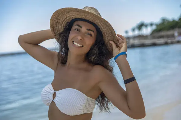 stock image Discover paradise with this stunning image of a tanned beauty under the Caribbean sun. Sexy smiling woman with an elegant straw hat, radiates confidence and charm as she enjoys the tropical ambiance.