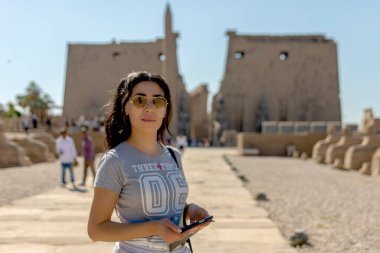 Tourist enjoying the timeless beauty of Luxor's Avenue of the Sphinxes connecting its temple to Karnak Connecting with the rich history of ancient Egypt and imagining the life of the pharaohs. clipart