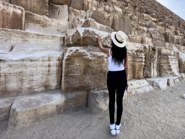 Bir turistin Keops Piramidi ile temas kurduğunu görmek, Giza, Mısır 'da bir dünya harikası. Bu yerin eski görkemini ve tarihsel önemini tecrübe edin..