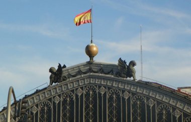Spain, Madrid, Plaza del Emperador Carlos V, Madrid Atocha railway station, sculptural group and flag on the roof of the building