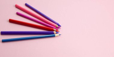 Renkli kalemler pembe arkaplanda bir nokta gösteriyor