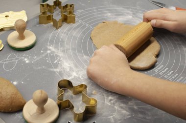 Zencefilli ekmek kalıpları, bir çocuk tarafından sarılmış hamur ve yuvarlanan bir paspas.