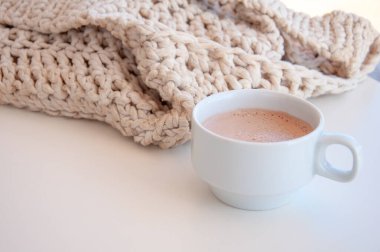 Cozy scene with cup of coffee and a knitted bag. Hygge style. Mug of black coffee standing on white table. Side view, vintage style. Still life clipart