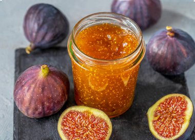 Cam kavanozda incir reçeli gri beton arka planda taze incir ve siyah taş tahta. - Yakın çekim. Üst Manzara. Seçici odak