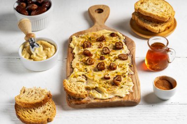 Yumuşak tereyağı, bal, tarçın, hurma ve beyaz ahşap arka planda crostini ile yapılan tatlı tereyağı tahtası. Seçici odaklanma. Üst Manzara. Trend gıda konsepti.