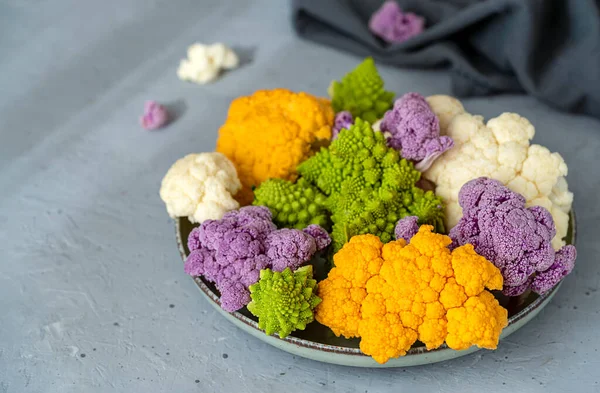 stock image Different cauliflower cabbage on plate and grey concrete background, grey napkin. Close up. Selective focus. Copy space. Healthy food concept